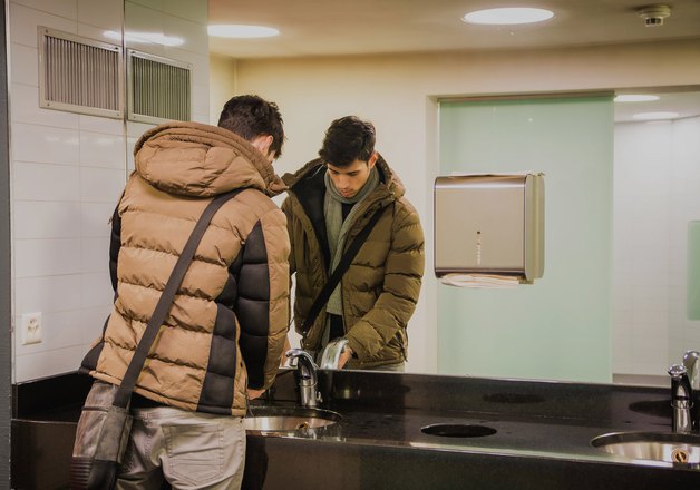 Installers fitting a restroom accessory